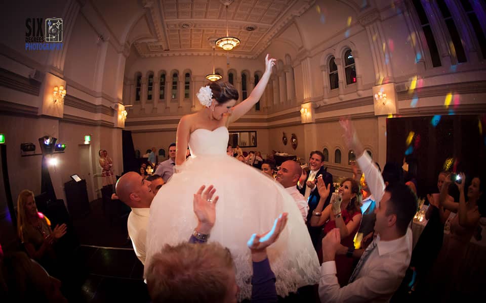 Bride lifted into air as guests dance around her at wedding celebration